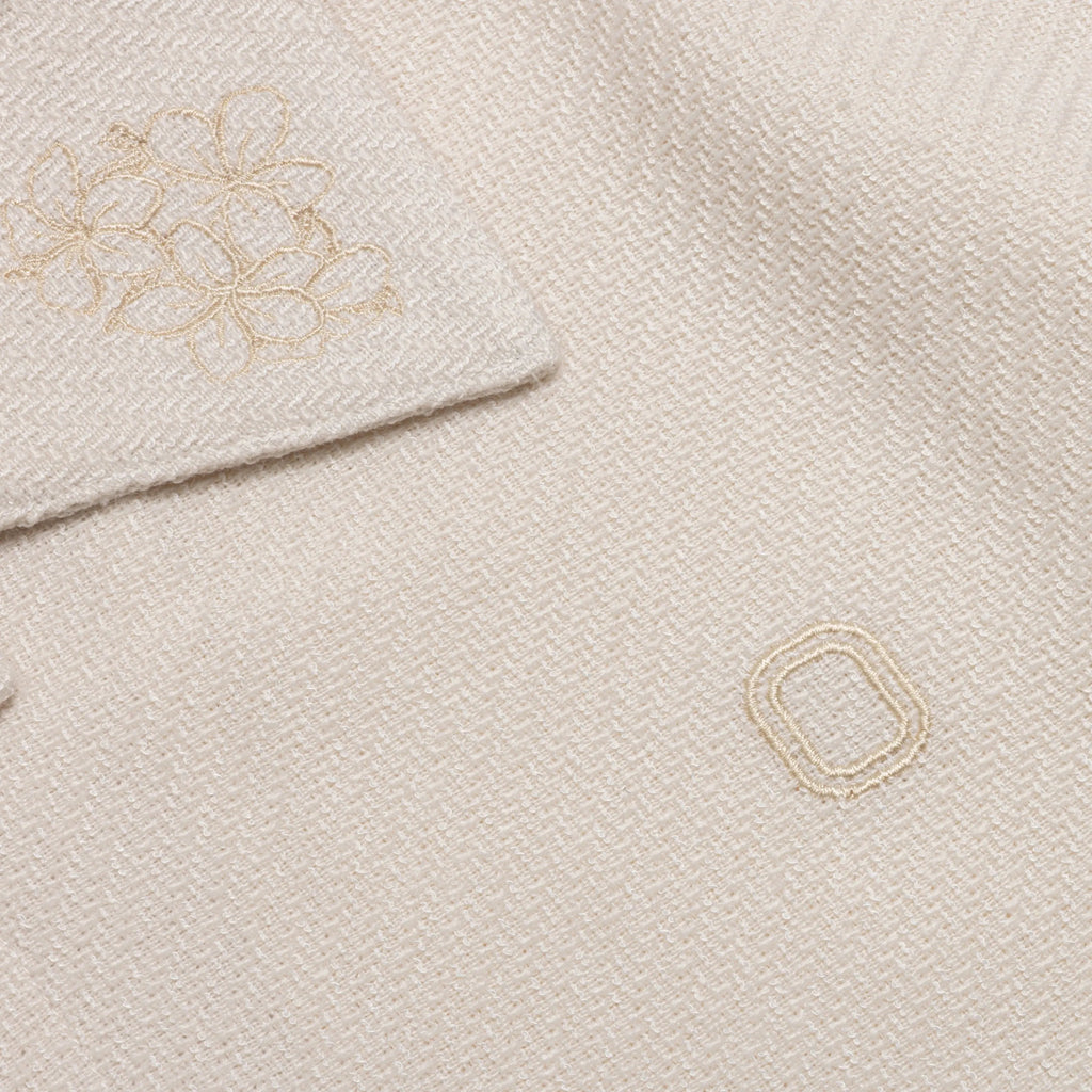 Close-up of embroidered 'O' logo and flower details on shirt