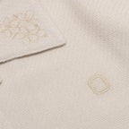 Close-up of embroidered 'O' logo and flower details on shirt
