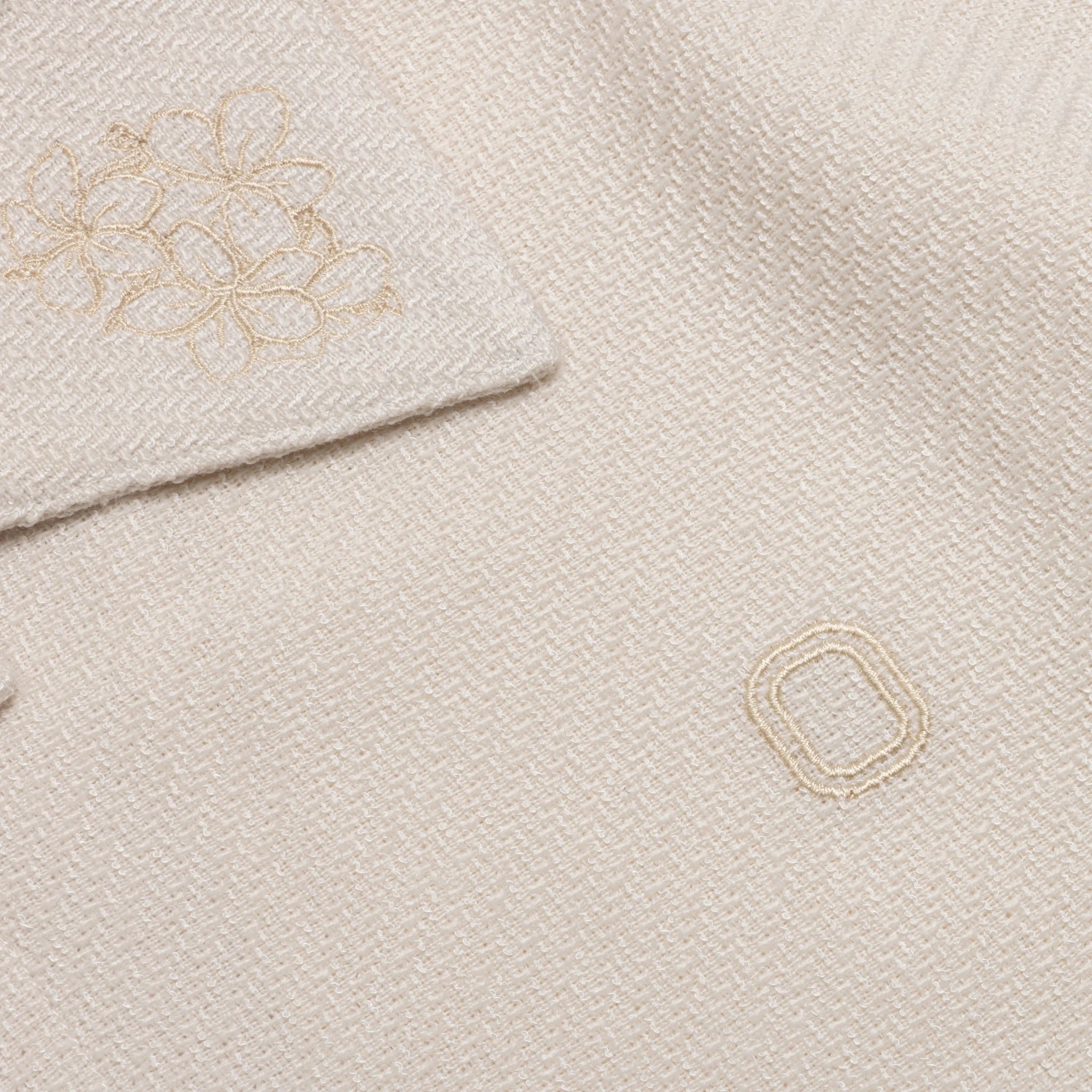 Close-up of embroidered 'O' logo and flower details on shirt