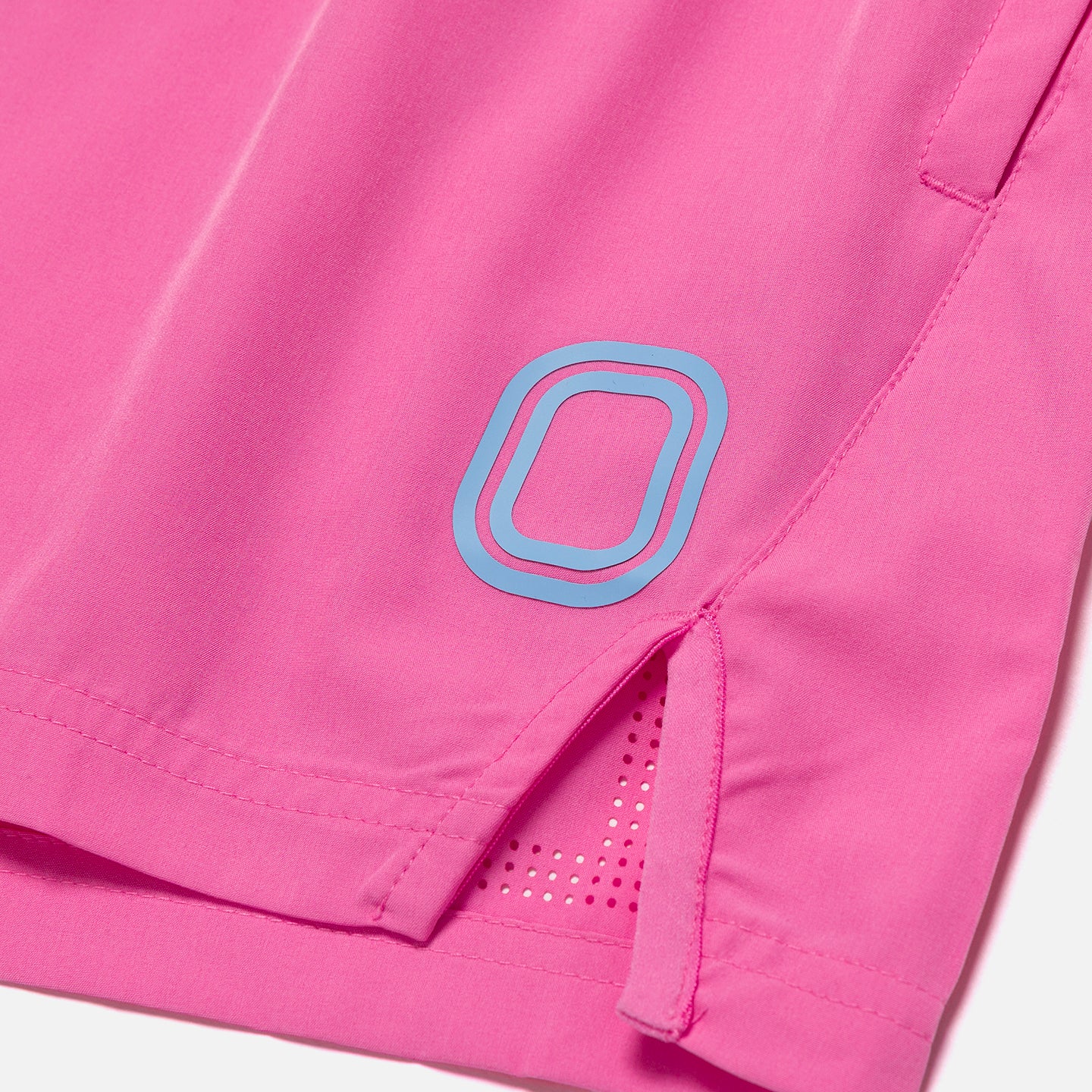 Close-up of pink shorts with a blue logo on a white background