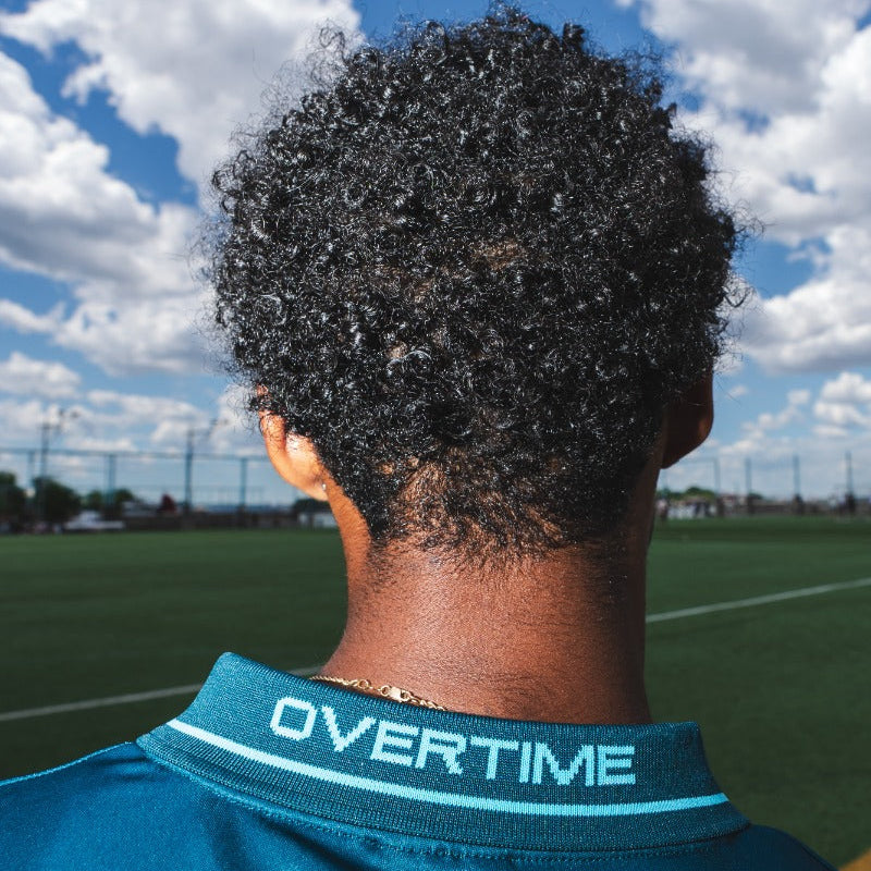 Person wearing a teal sports jersey with "OVERTIME" on collar